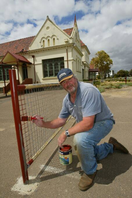 Warrnambool Primary Schools principal Howard Looney painting the school fence while on holidays.