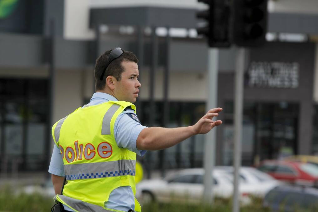 A police officer replaces traffic lights at the corner of Gateway Road and Raglan Parade yesterday afternoon.