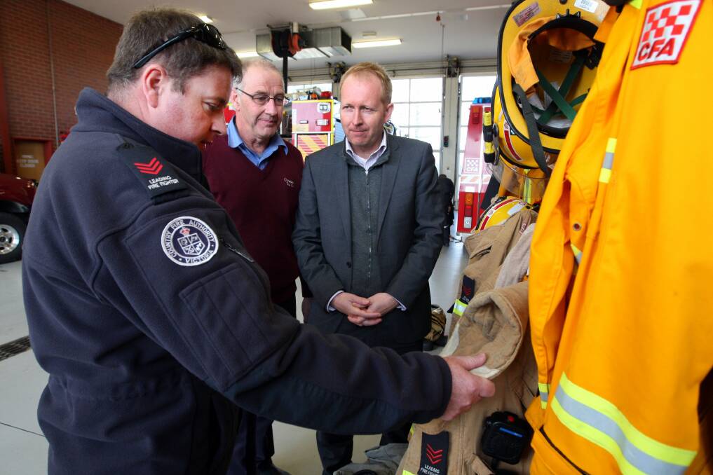 Leading Firefighter Troy Cleverley and Warrnambool Fire Brigade chairman Malcolm Bishop show Victorian Greens Leader Greg Barber showing him how clothing is stored in the engine room collecting fumes. Picture:LEANNE PICKETT