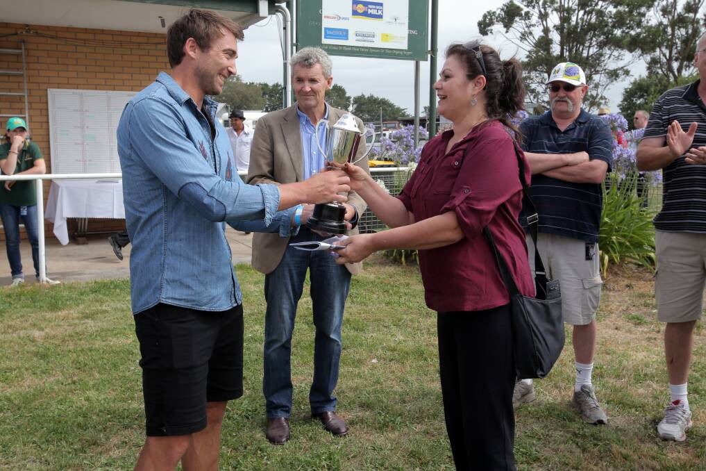 Geelong footballer Corey Enright handing the trophy over to Jessie Bainbridge.