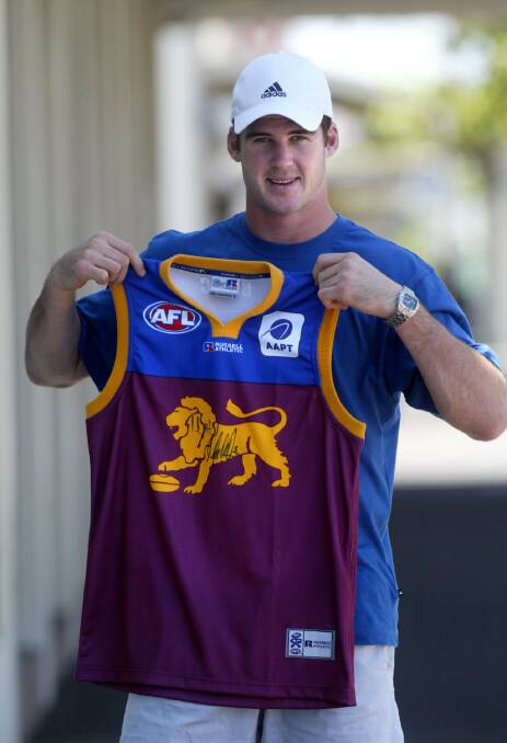 Brisbane Lions football player Jonathan Brown with a signed Lions jumper to be auctioned for Relay for Life.