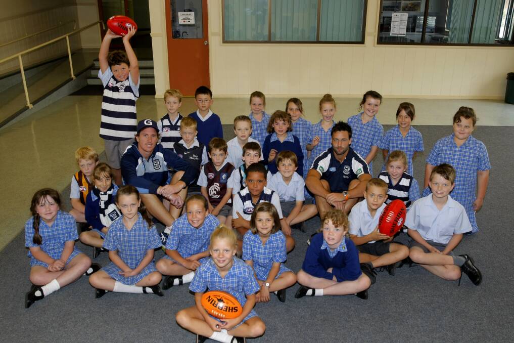 Geelong players Mitch Brown and Jimmy Bartel sit with the King's College grade three students before running a skills clinic. 