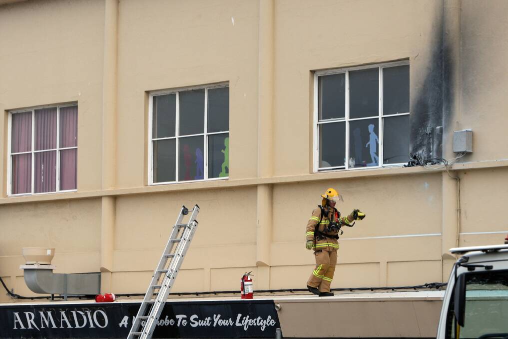 A CFA officer checks the power box fire area above Armadio shop, blocking off traffic on Koroit and Liebig Streets.