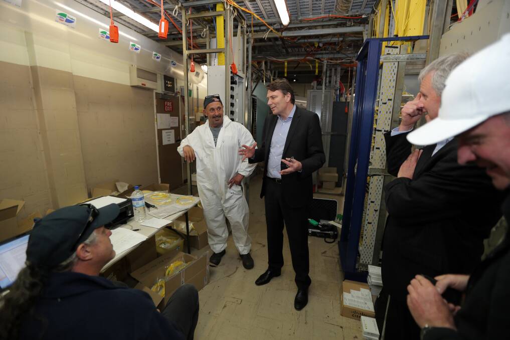 Telstra CEO David Thodey inspecting the Warrnambool exchange building and speaking to two technicians. 