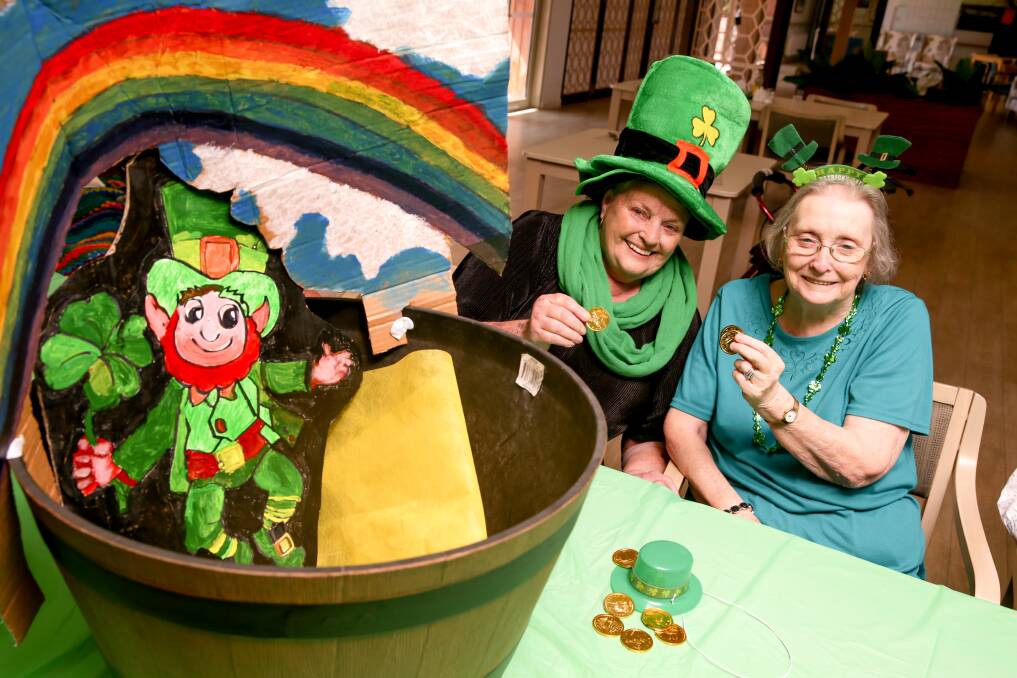 LUCK: Mercy Place residents Liz Stacey and Jenny Walker toss some chocolate coins into the well for good luck. Picture: Chris Doheny