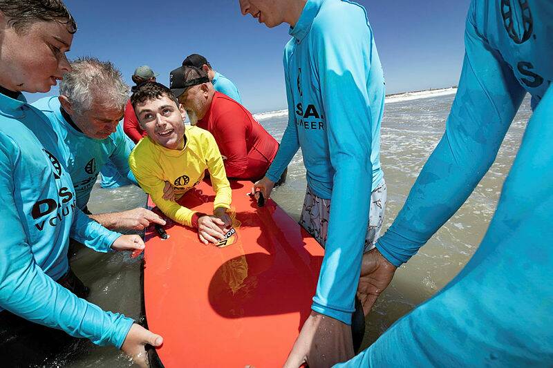 Bailey Harding surfs with volunteers. Picture by Sean McKenna