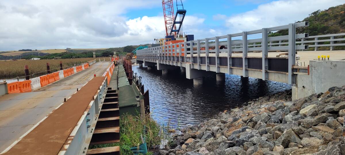 The temporary, floating bridge across the Gellibrand River compared to the permanent Old Coach Road bridge which is under construction. Picture supplied.