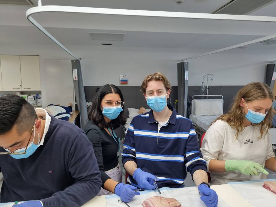 HANDS-ON: South West Healthcare surgical registrar Dr Marina Youssef teaches Xavier Dowd suturing techniques as part of the students' three-day tour of Warrnambool.
