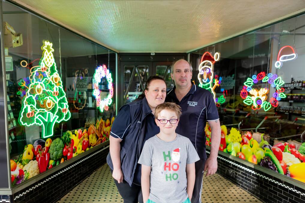 Cassie, Jason and Jordan Greaves stand outside the Christmas display at their Terang grocer, Greavesys. Cassie drew the designs for the neon lights herself, before submitting them as a custom order. Picture by Anthony Brady