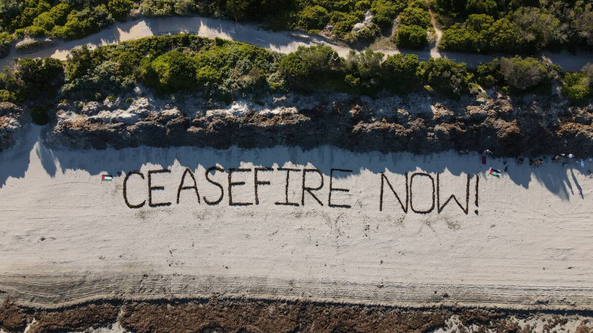 A 55-metre sign along the sand at Lady Bay beach that reads ceasefire now! Picture by Colleen Hughson