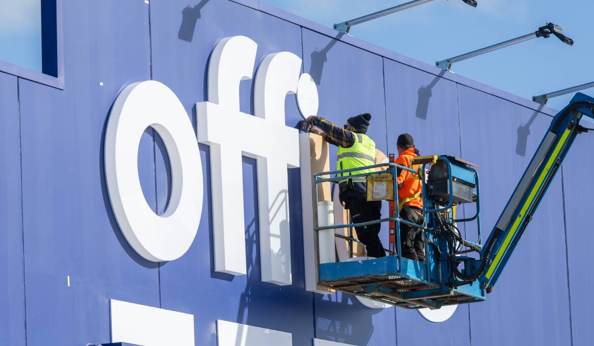Workers in a cherry picker put up the Officeworks signage at the front of the store in July. Picture by Eddie Guerrero