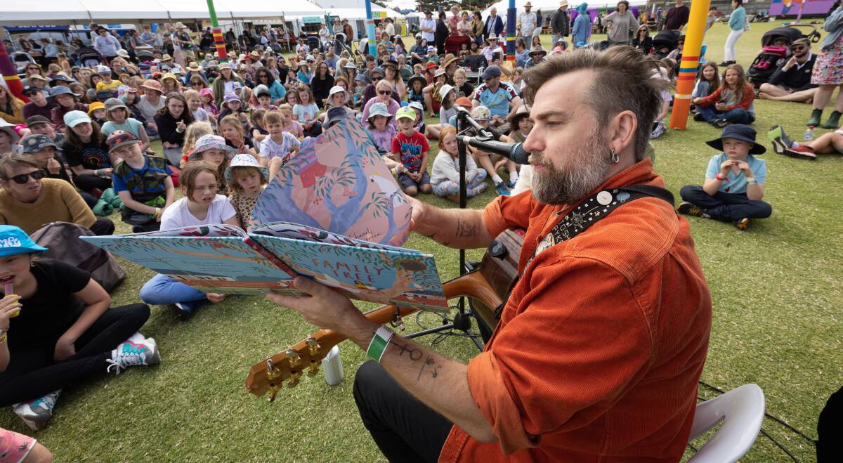 Josh Pyke, who has family links to the town's Mott's Cottage, reads his book to children at the 2023 Port Fairy Folk Festival. Picture by Sean McKenna