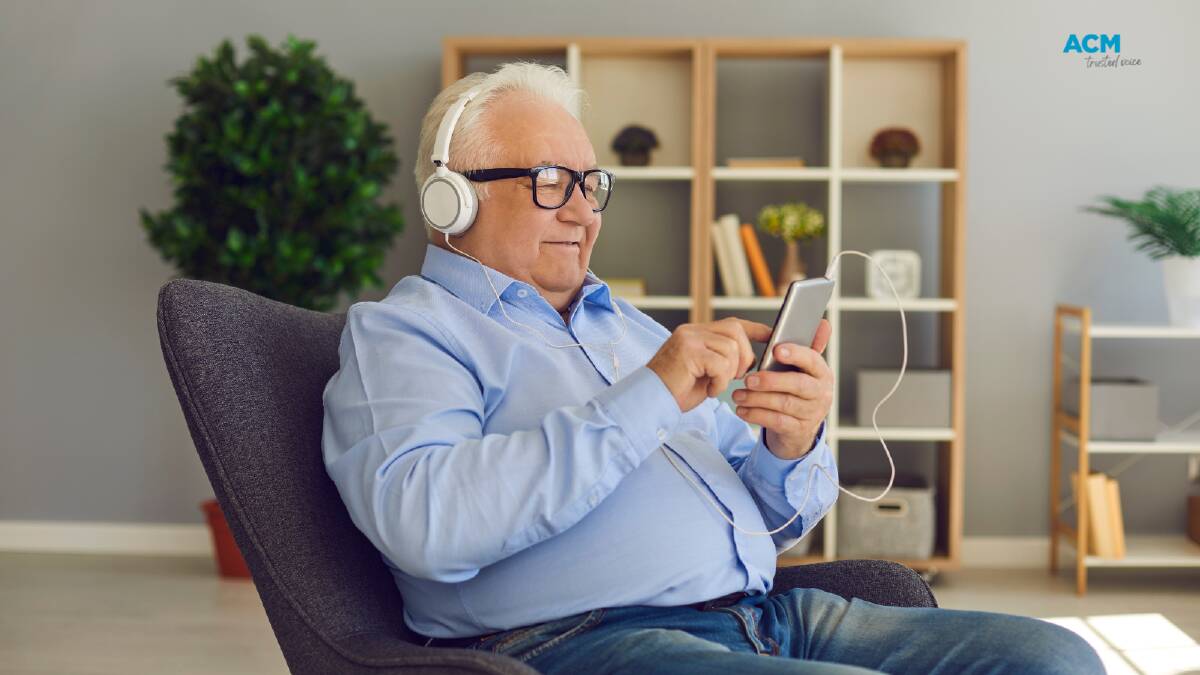 A man sits in an armchair listening to radio through headphones. File Picture. 
