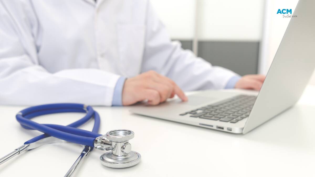 A doctor works on a laptop with a stethoscope in the foreground. File picture.