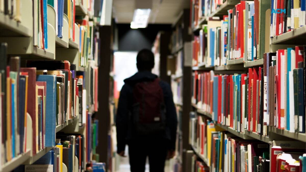A figure walks through rows of books in a library. File picture. 