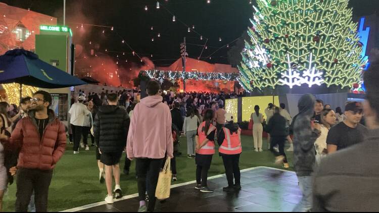 Fans pack into Melbourne's festively decorated Federation Square with red flares in the background. File picture.