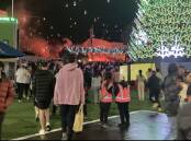 Fans pack into Melbourne's festively decorated Federation Square with red flares in the background. File picture.