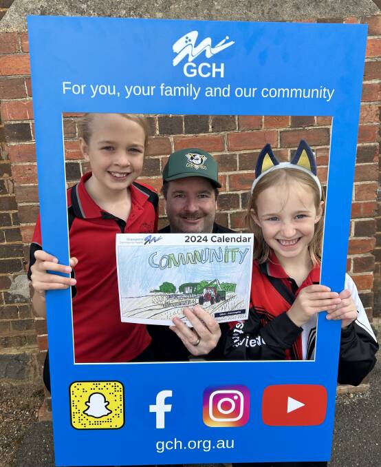 GCH social media content creator Gareth Olver shows off a GCH 2024 calndar illustration with his kids, Siobhan and Cailin. Picture supplied