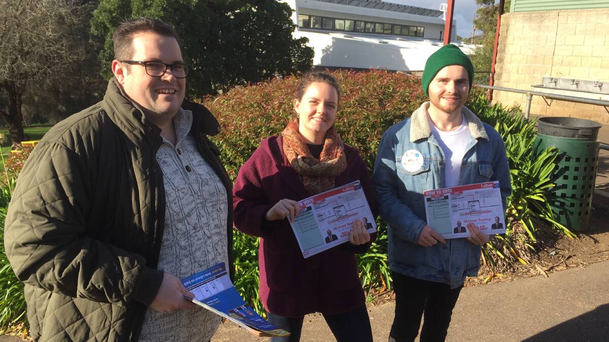 At Woodford polling booth are Jarrod Woolley (left), handing out Liberal how-to-vote flyers, and son of the Labor candidate Michael Barling, Daniel Barling, and his partner Erin Fennessy, not surprisingly supporting Labor.