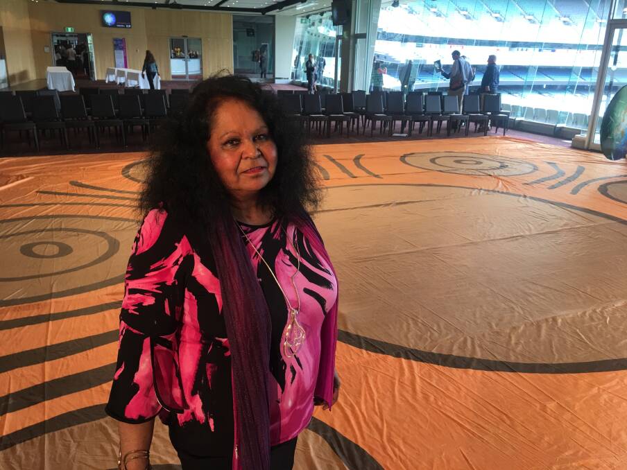 HONOURED: Artist Fiona Clarke stands on a giant silk reproduction of her Walkabout Wickets artwork at the launch of Cricket Australia's reconciliation action plan at the MCG.