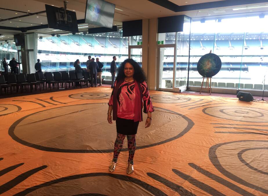 HONOURED: Artist Fiona Clarke stands on a giant silk reproduction of her Walkabout Wickets artwork at the launch of Cricket Australia's reconciliation action plan.