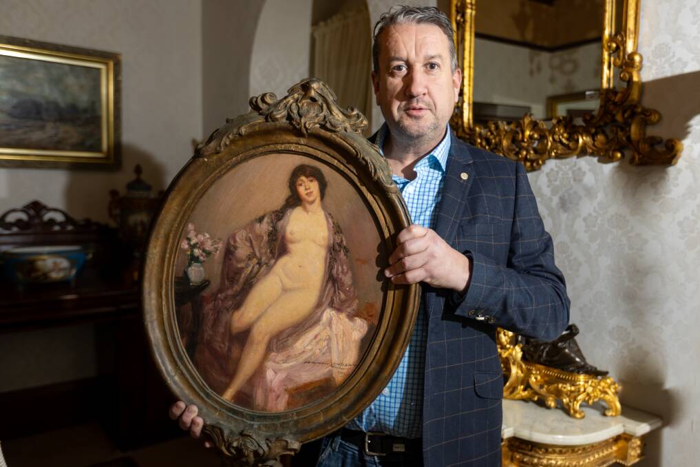 Auctioneer Christian McCann holds a Norman Lindsay artwork that will be auctioned on Sunday. Picture by Eddie Guerrero