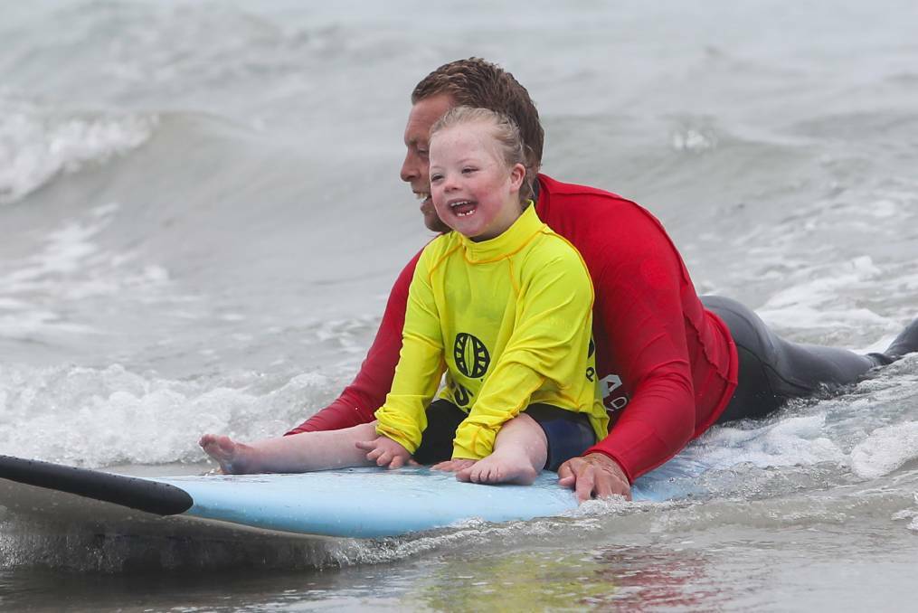 Happy days: Participant Adia Herry, 6, surfs a wave at Warrnambool's Lady Bay with the help of a volunteer at a previous event. There were smiles all around as participants made the most of the day. Pictures: Morgan Hancock