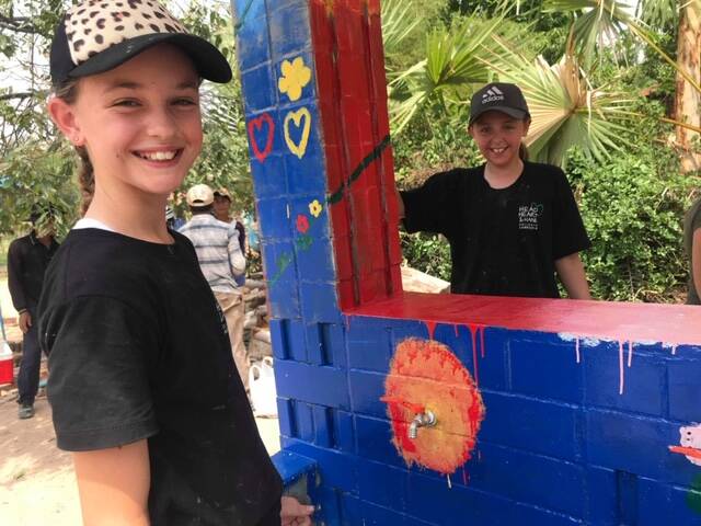 ALL SMILES: Charli Dillon and her cousin Bella help construct a wash house at a school in Cambodia. Picture: Supplied