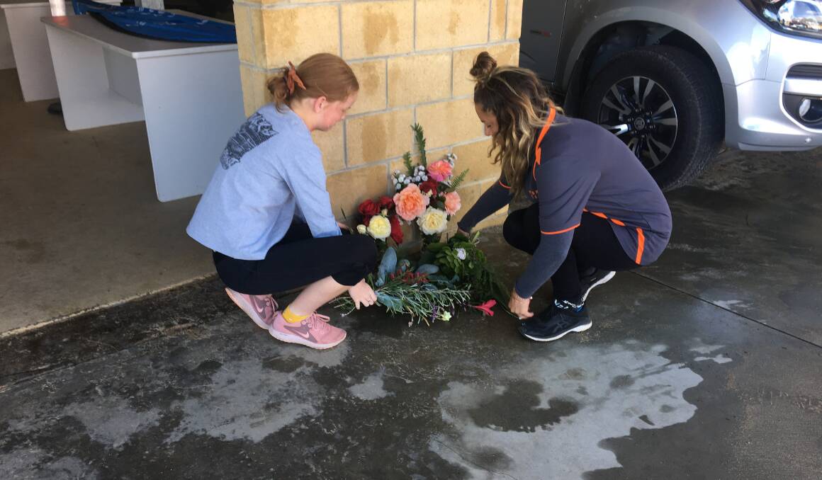 Tribute: Two females leave flowers at the Port Campbell Surf Life Saving Club on Monday.
