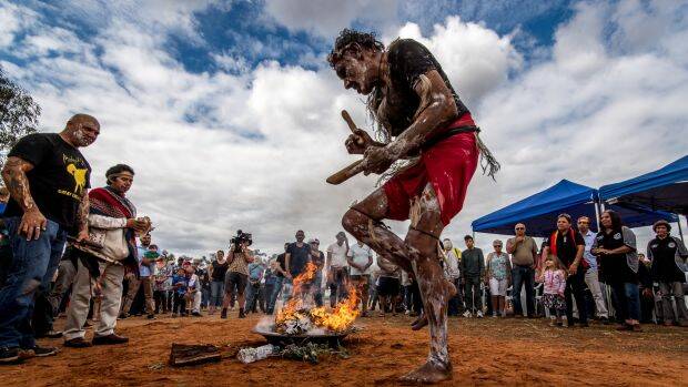 Fire and smoke are the companions of the 105 repatriated ancestors throughout their journey back to country. Mutthi Mutthi elder David Edwards performs a ceremonial dance at Balranald, NSW. Photo: Justin McManus