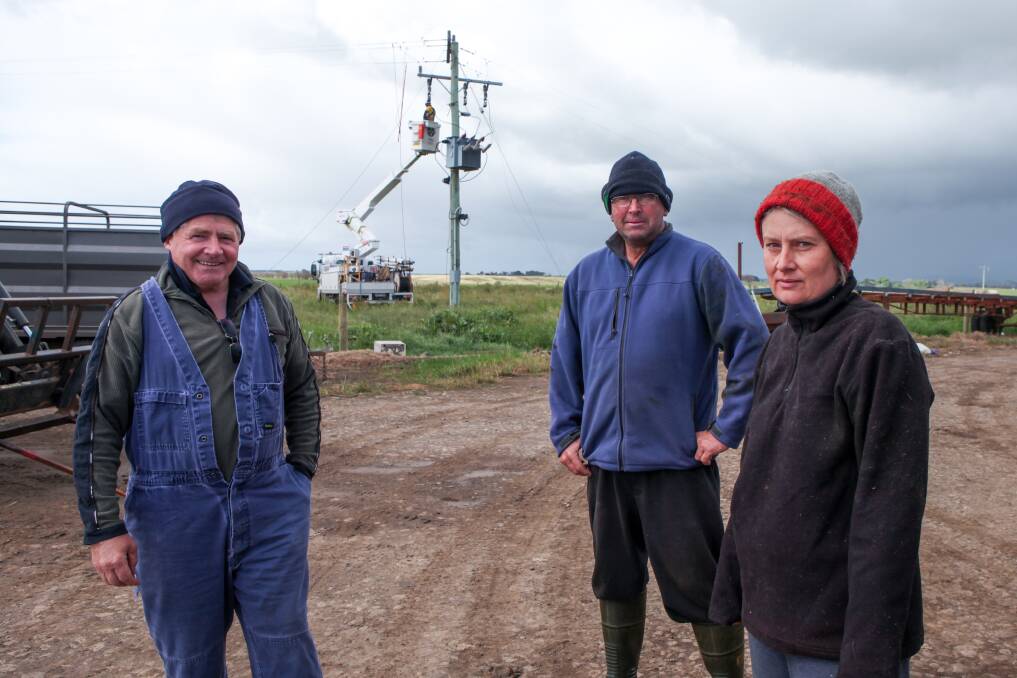 Time for change: The Sisters dairy farmers Jack Kenna (left) and Brad and Jill Porter, as Central Energy line workers repair a powerline that had fallen down on the Porter's property near where the Garvoc fire started on St Patrick's Day. Picture: Rob Gunstone

