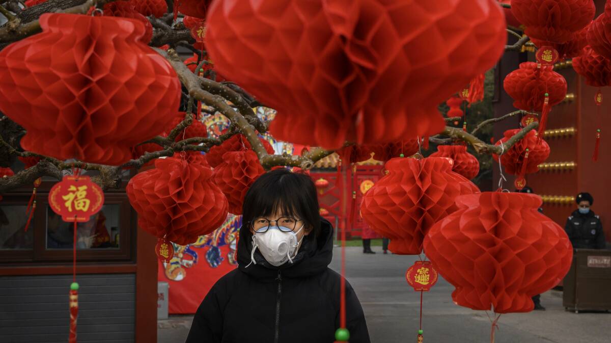 Worrying: A Chinese woman wears a protective mask as she stands with decorations marking the Chinese New Year holiday at the site of a temple fair that was cancelled on Sunday in Beijing. The number of cases of a deadly new coronavirus has risen to over 2000 in mainland China as health officials locked down the city of Wuhan in an effort to contain the spread of the pneumonia-like disease. Medical experts have confirmed the virus can be passed from human to human.