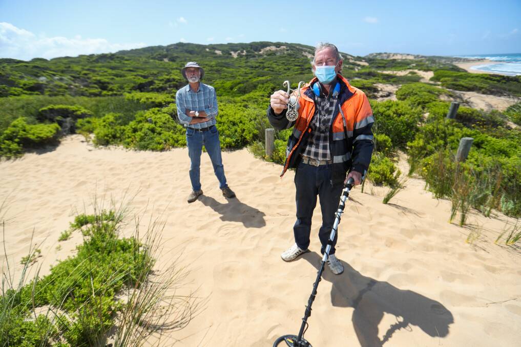 KEEPING LEGEND ALIVE: John Sherwood alongside Ross Poulter, who has found a brass emblem he believes is from the 17th or 18th century while using a metal detector in the dunes. Picture: Morgan Hancock 