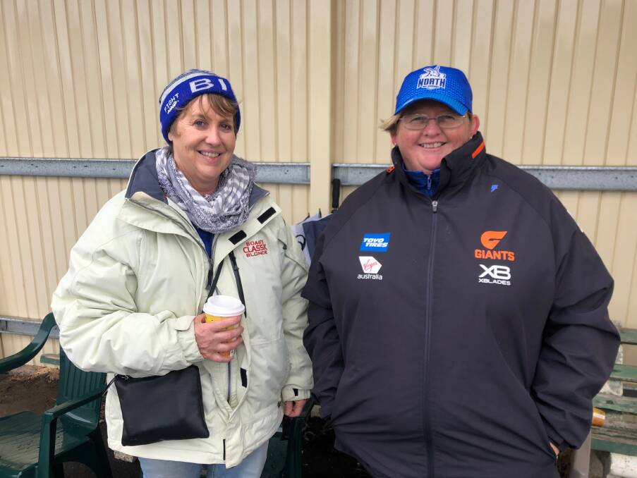 Staying dry: Jodie McIntosh, of Digby and Rose Wombwell, of Heywood support the netballers at the HFNL grand final. Picture: Kyra Gillespie