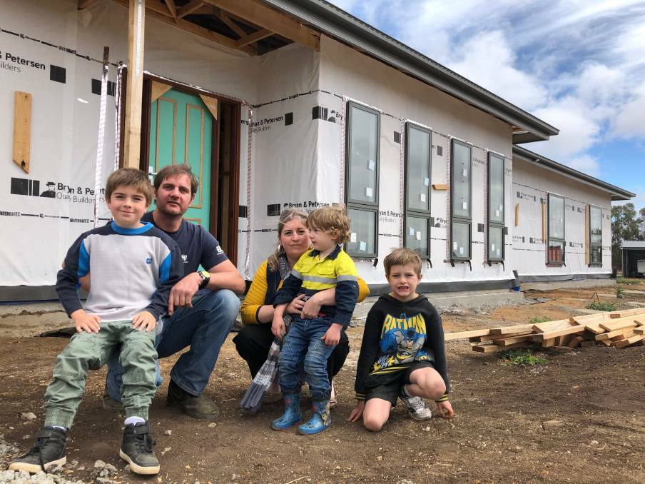 Adam Rowe and Tara-Lee Salau with their children Zachary, Harrison, and Oliver, pictured in 2019 rebuilding after their property was razed in the St Patrick's Day inferno. 