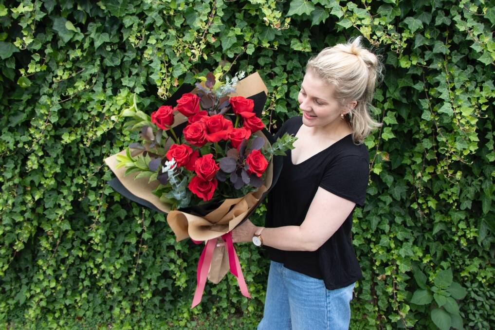 O'Grady's Florist co-owner Jessica Advincula with a bouquet of red roses. 