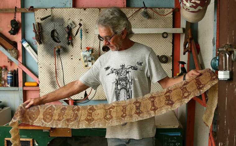 Kim Tuckwell of Singleton Heights with the shed skin of his pet snake. Picture: Marina Neil