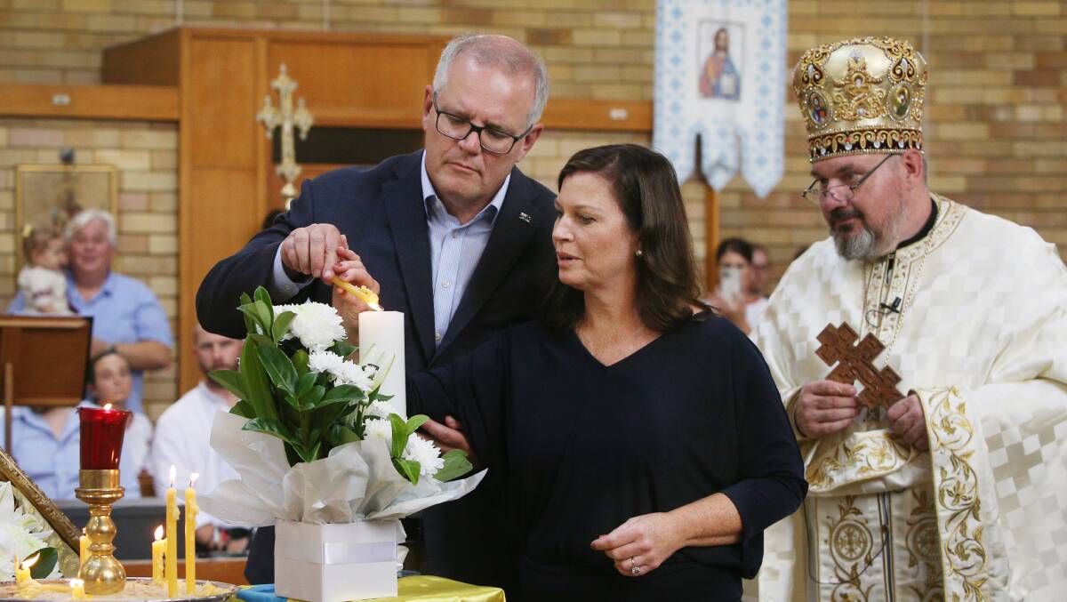 Prime Minister Scott Morrison and wife Jenny light a candle during a service at St Andrew's Ukrainian Catholic Church at Lidcombe on Sunday. Picture: Getty Images