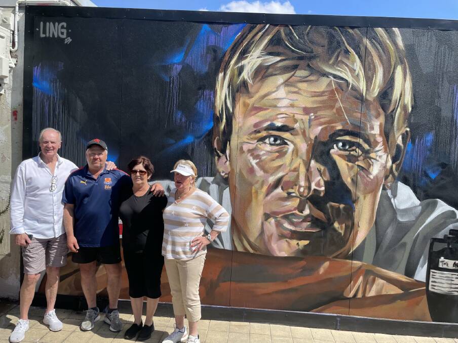 Shane Warne's parents Keith and Brigitte, at each end of the group, join cafe owners Gary and Louise Abley in front of the giant mural at Violet Town. Picture supplied.
