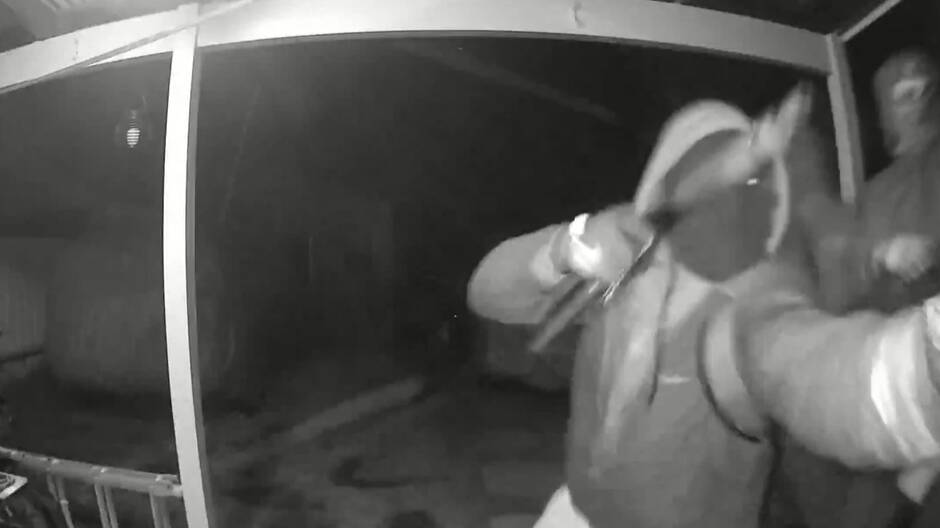 A still of a video which showed men armed with a machete and a shotgun attempt to break into a home. Picture by NSW Police.