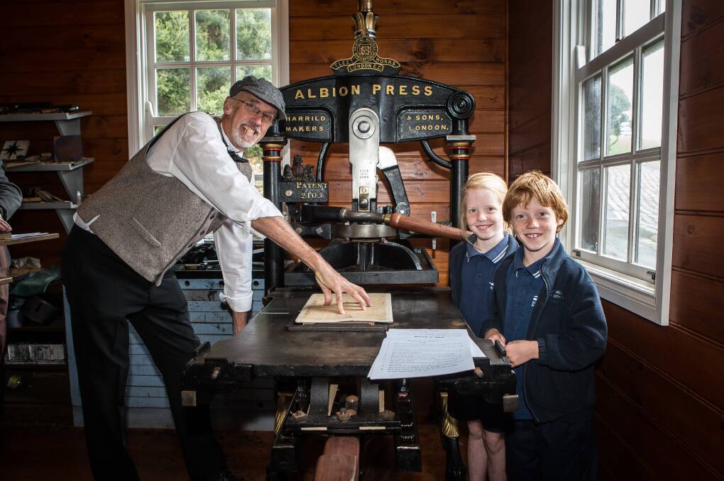 LEARNING: Flagstaff Hill's Andrew Barrie shows Merrivale Primary School's Rhylee and Jasper Moore, 8, how to use a printing press as part of Education Week activities. Picture: Christine Ansorge