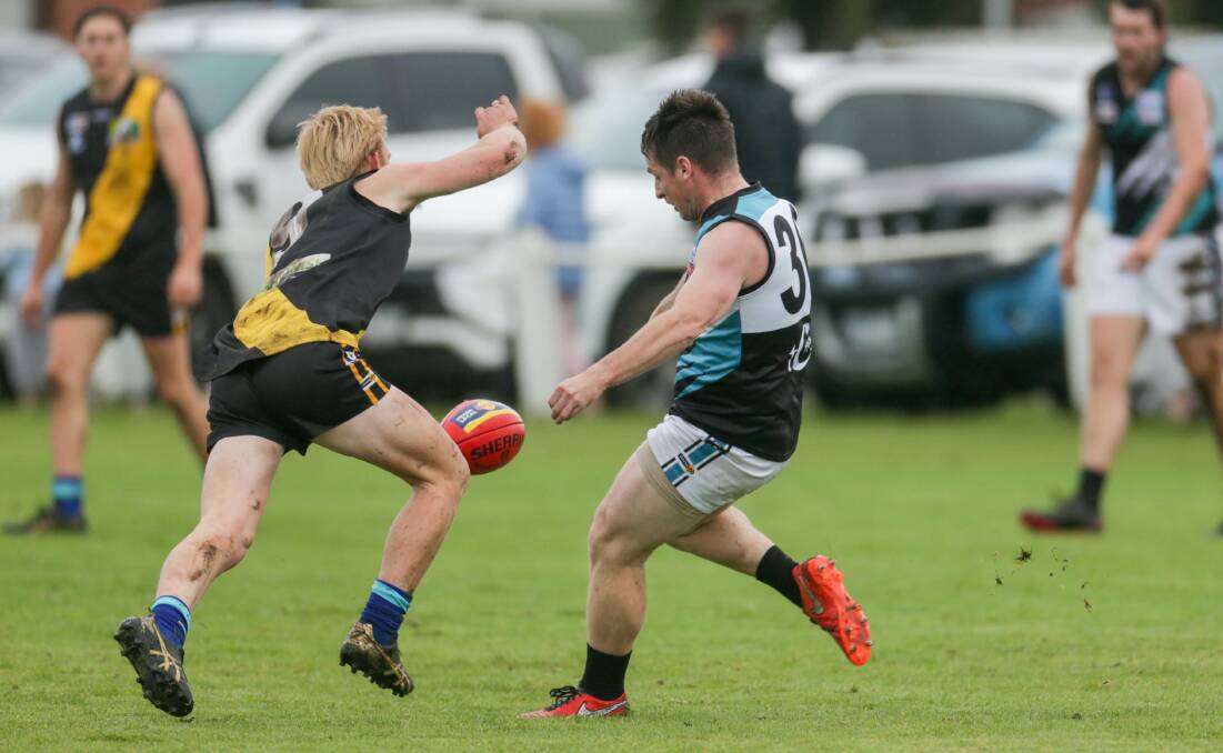 SIDES TO MEET: Kolora-Noorat playing-coach Ben Walsh gets a kick away under pressure from Merrivale's Tate Porter. Picture: Chris Doheny