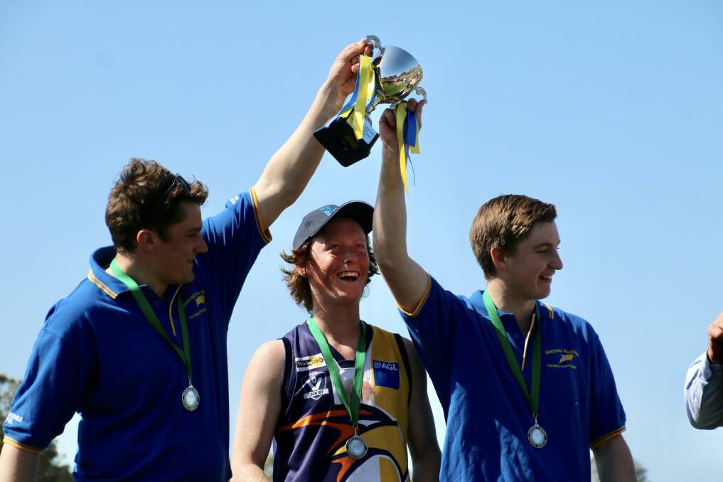 Lifting the cup: Hawkesdale-Macarthur under 16.5 football co-coaches Paddy Kelly and Charlie Summers with captain Hamish Wortley after the premiership win. Picture: Tracey Kruger.