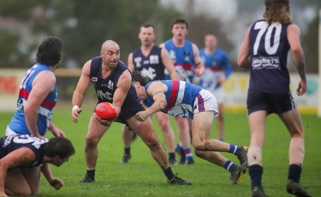 Standing tall: Nirranda's Peter McDowall gets a handball away under pressure against Panmure last weekend. The Warrnambool and District league has released a revised draw. Picture: Morgan Hancock 