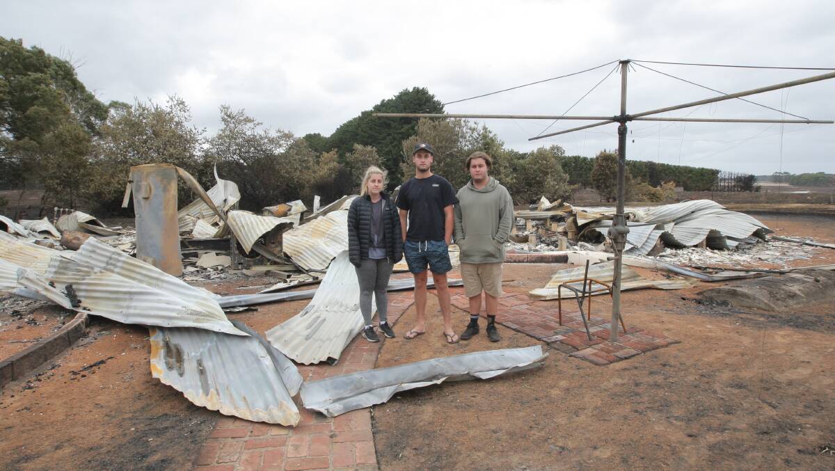 REBUILD: Vicki Angus's three children Ellie, Sylas and Taj Merrett in what was left of their burnt home after the St Patrick's Day fires. 

