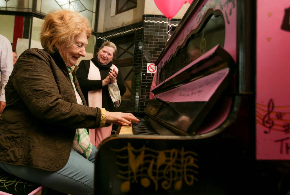 Vibrant: Trish Storr watches on as Terang musician Marie Ewing plays a donated pink street piano, painted by local artists, that has taken pride of place in Terang's Johnstone Court where community members can play an impromptu tune for people passing by. Picture: Chris Doheny