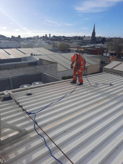A Warrnambool SES volunteer works on the roof of the city's police station on Thursday. Picture supplied