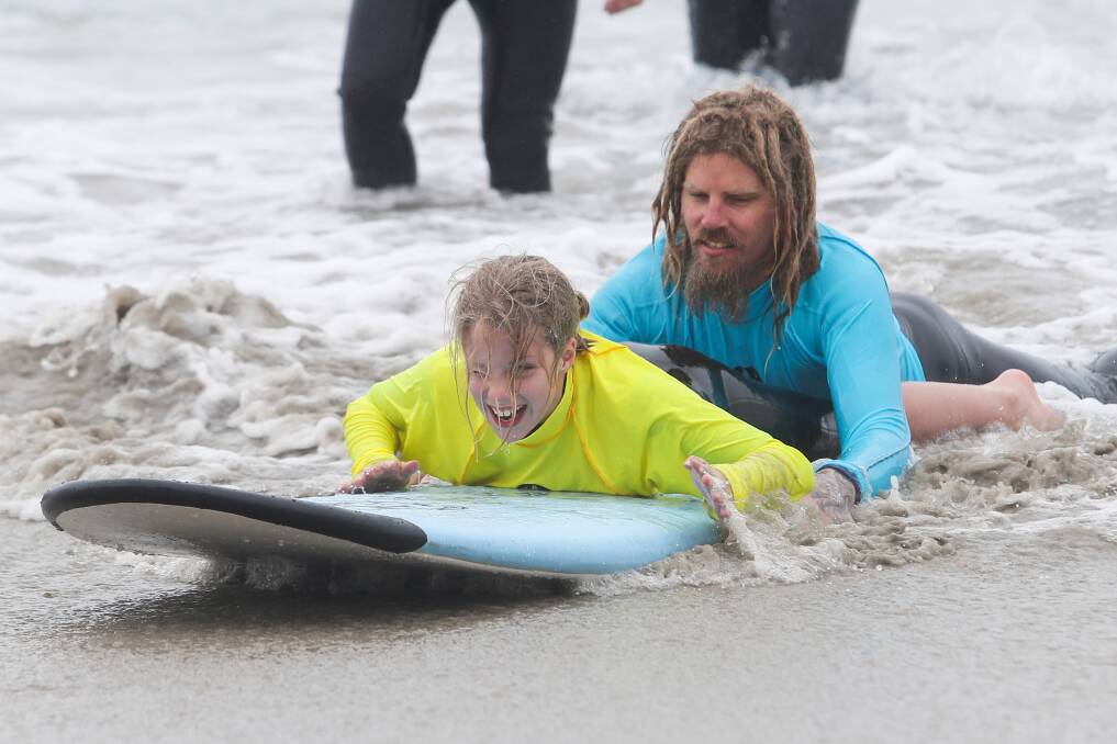 New skill: Lily Mitchell, 11, rides a wave into shore with help from a volunteer on Saturday. Picture: Morgan Hancock
