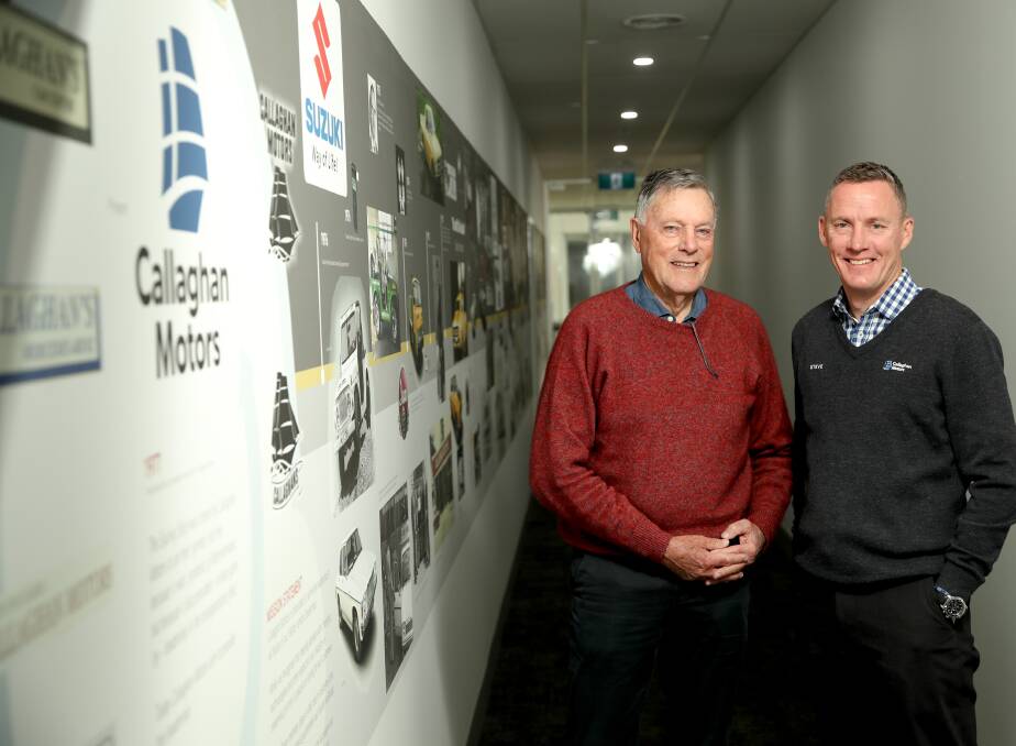 Former and current Callaghan Motors dealer principals Brian and Steve Callaghan at the dealership's history wall which includes some of the milestone highlights The Standard has covered. Picture by Chris Doheny.
