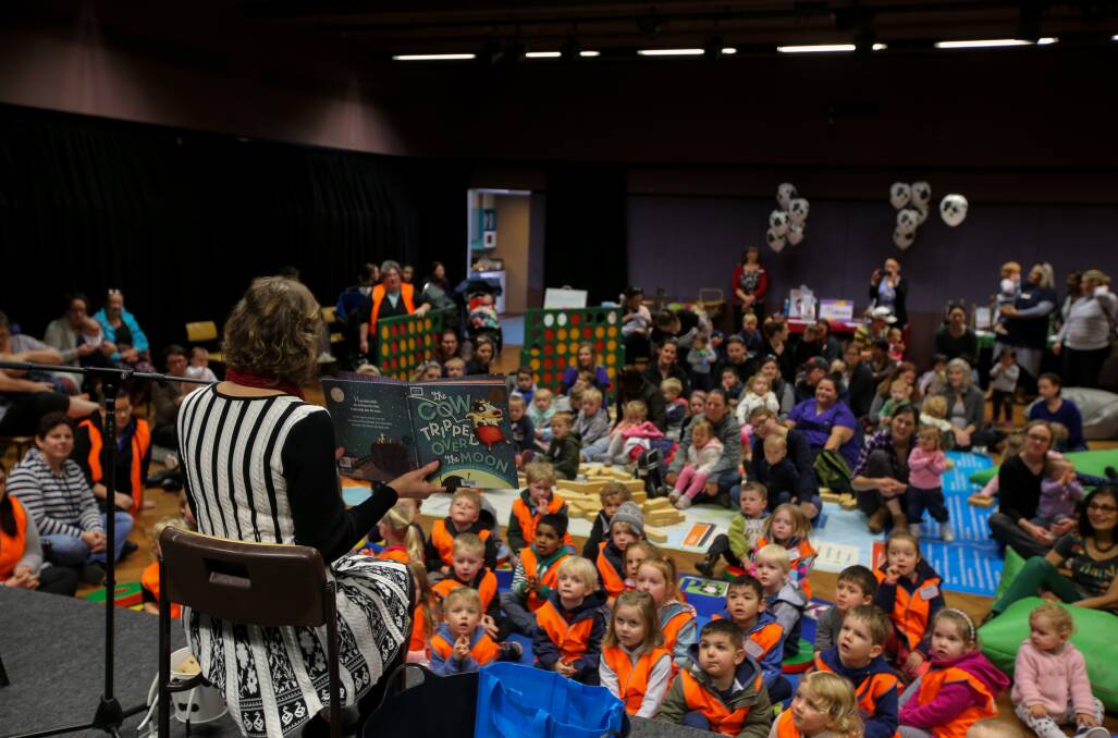 Bookworms: Library officer Julie Struth reads The Cow Tripped Over The Moon to children and adults as part of National Simultaneous Storytime. Picture: Rob Gunstone